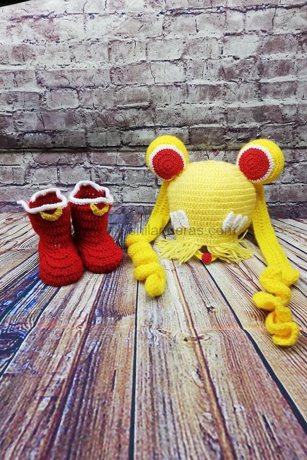 Un bebé con gorro amarillo y un osito con gorro tejido a crochet